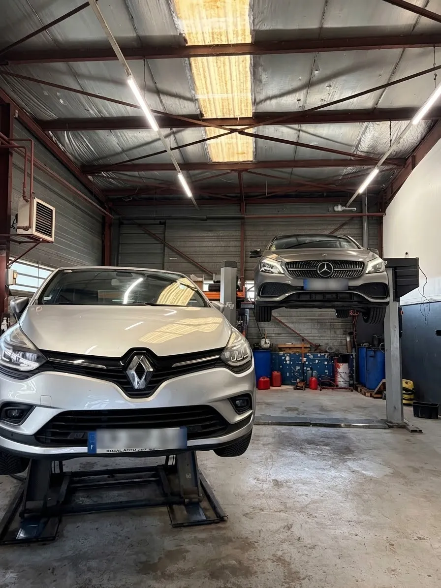 Deux véhicules sur les ponts élévateurs dans l'atelier du Garage QLM